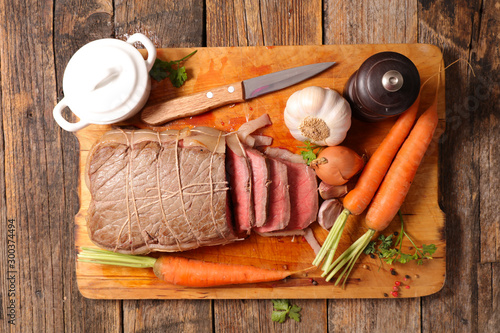 roast beef with carrot and sauce on wooden board