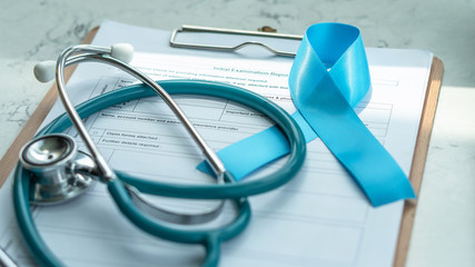 Blue awareness ribbon for prostate cancer, men health and diabetes in November with light blue bow color on medical doctor record, male patient healthcare concept