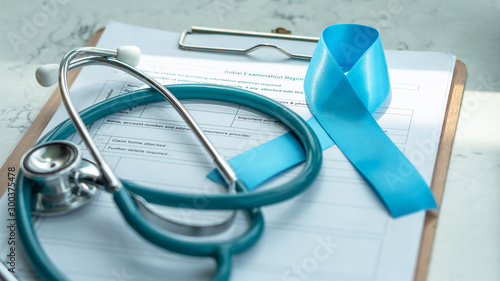 Blue awareness ribbon for prostate cancer, men health and diabetes in November with light blue bow color on medical doctor record, male patient healthcare concept photo