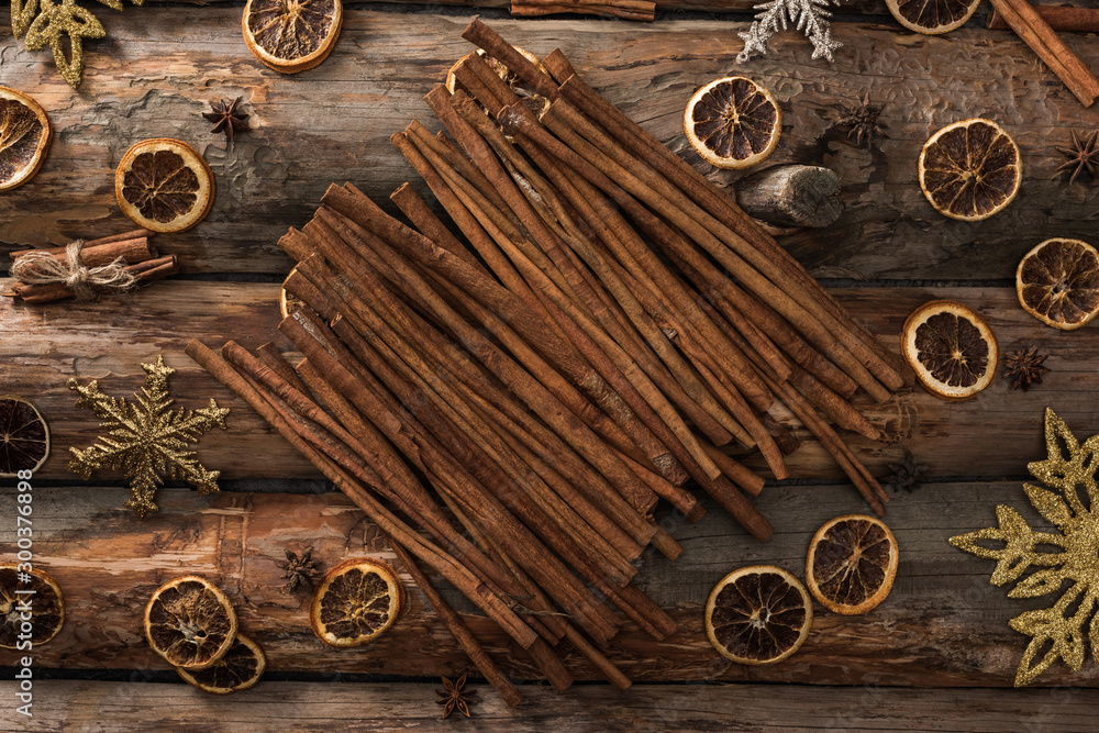 top view of cinnamon sticks near anise, dried citrus slices and snowflakes on wooden background top view of cinnamon sticks near anise, dried citrus slices and snowflakes on wooden background
