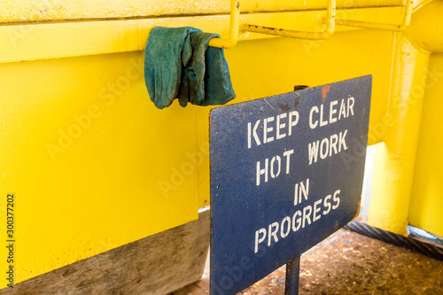 Signage 'keep clear hot work in progress' on deck of a construction barge