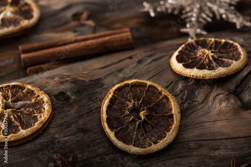 dried citrus slices, cinnamon sticks and decorative snowflake on wooden background
