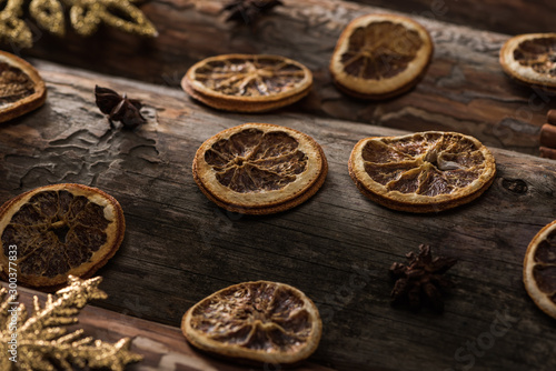 dried citrus slices with anise and decorative snowflakes on wooden background