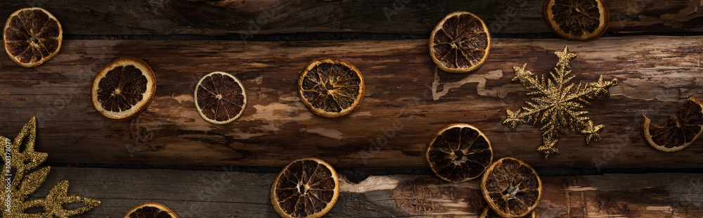top view of dried citrus slices and decorative snowflakes on wooden background, panoramic shot