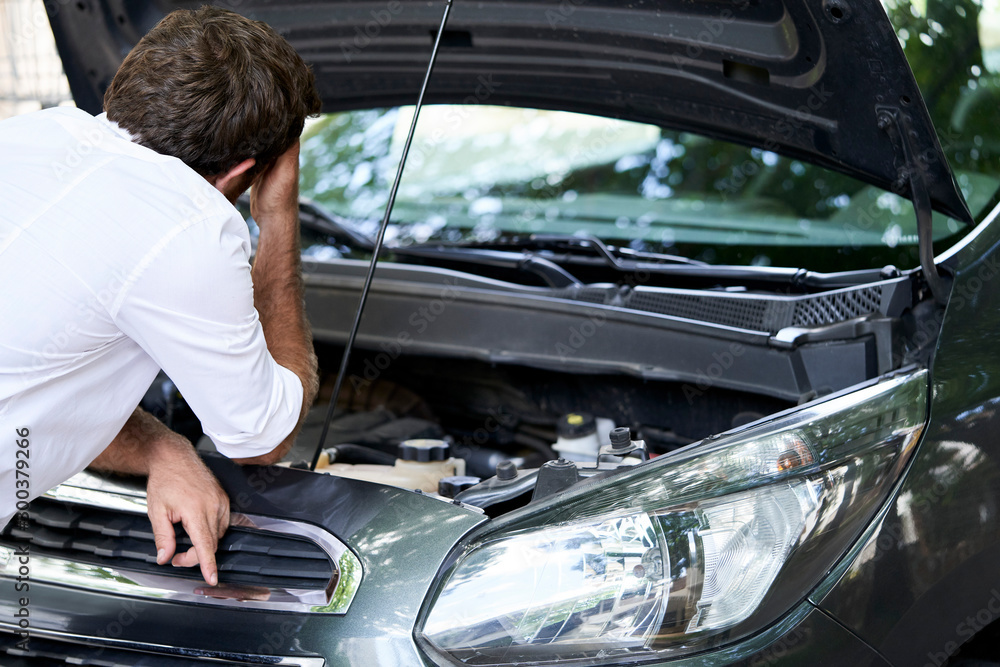 Rear view of frustrated man standing by broken car Rear view of frustrated man standing by broken car