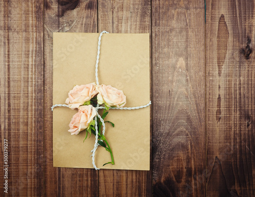 Kraft envelope, old paper tied with rope, old twine, on top of gently pink roses, the concept of a gift, a surprise. congratulations on Valentine's day, happy birthday. I love you
