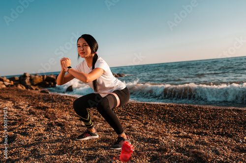 Concept of sport and healthy lifestyle. A woman in sports clothes is engaged in an exercise with an elastic band, a shaker lies near her legs. Copy space