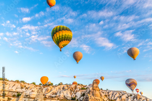 Colourful hot air balloons floating towards peaks in the valley of Göreme