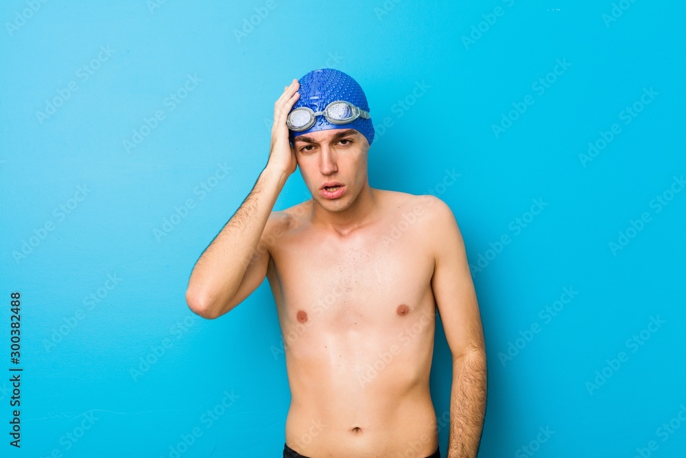 Young swimmer man tired and very sleepy keeping hand on head.
