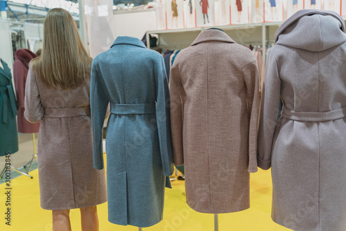 Warm coats are dressed on mannequins in clothing store. One of the mannequins is a slim young lady with long brown hair. photo