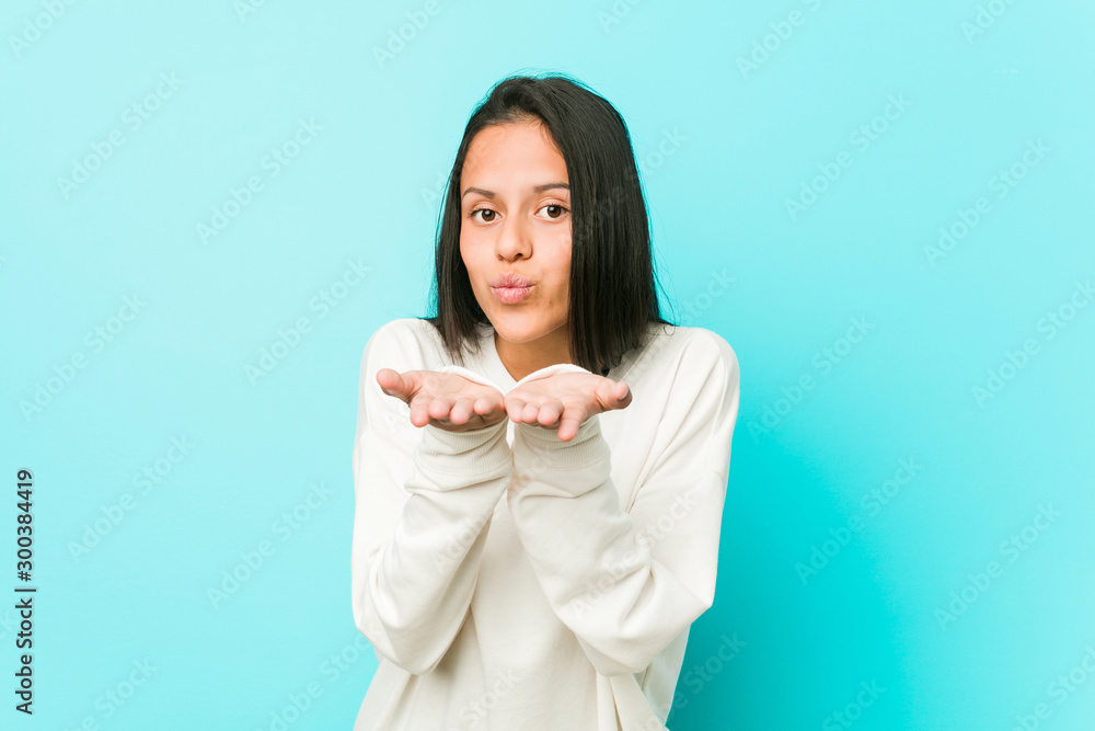 Young pretty hispanic woman folding lips and holding palms to send air kiss. Young pretty hispanic woman folding lips and holding palms to send air kiss.