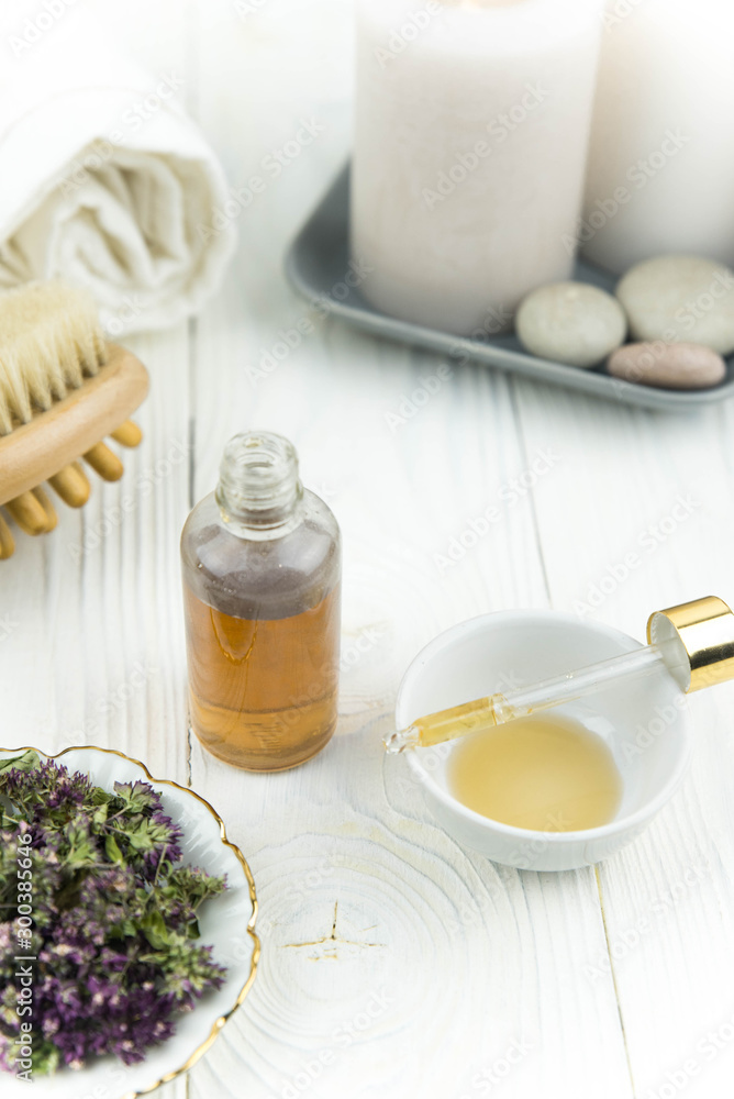 Spa treatment bottle of natural organic oil essence serum collagen. Towel, aromatic candles, flowers, massage brush and Buddha on white background. Copy space for text. Beautiful woman hands. Oil drop Spa treatment bottle of natural organic oil essence serum collagen. Towel, aromatic candles, flowers, massage brush and Buddha on white background. Copy space for text. Beautiful woman hands. Oil drop