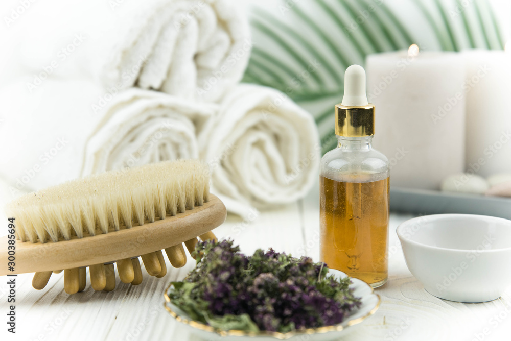Spa treatment bottle of natural organic oil essence serum collagen. Towel, aromatic candles, flowers, massage brush and Buddha on white background. Copy space for text. Beautiful woman hands. Oil drop Spa treatment bottle of natural organic oil essence serum collagen. Towel, aromatic candles, flowers, massage brush and Buddha on white background. Copy space for text. Beautiful woman hands. Oil drop