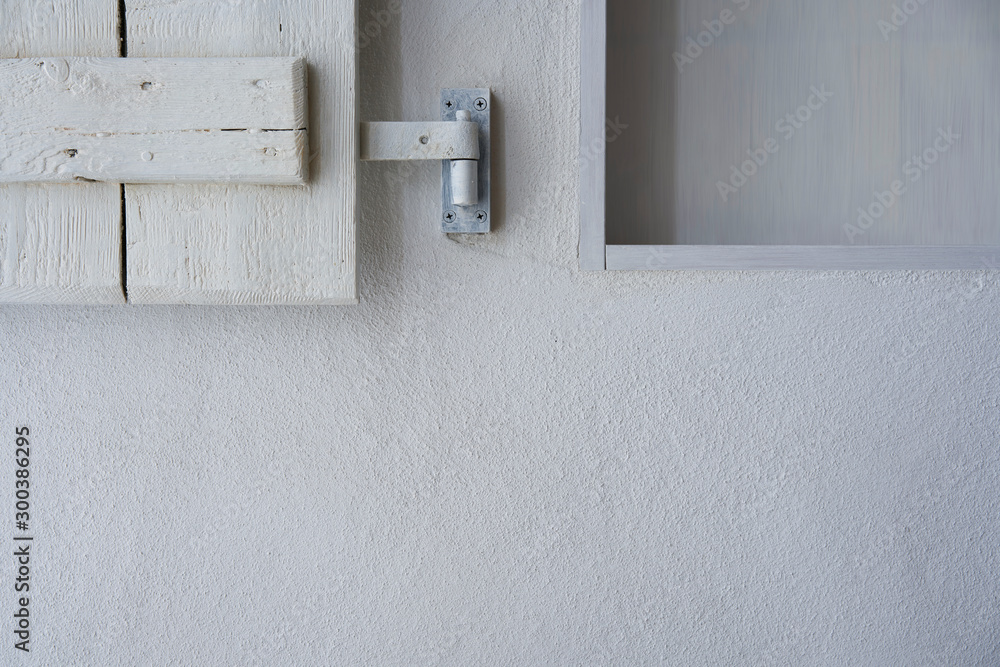 White wall with part of empty shelf and wooden shabby shutter White wall with part of empty shelf and wooden shabby shutter