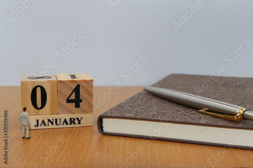 January  4, a calendar photo from the wood The table top consists of a book and pen that is ready to use. White background