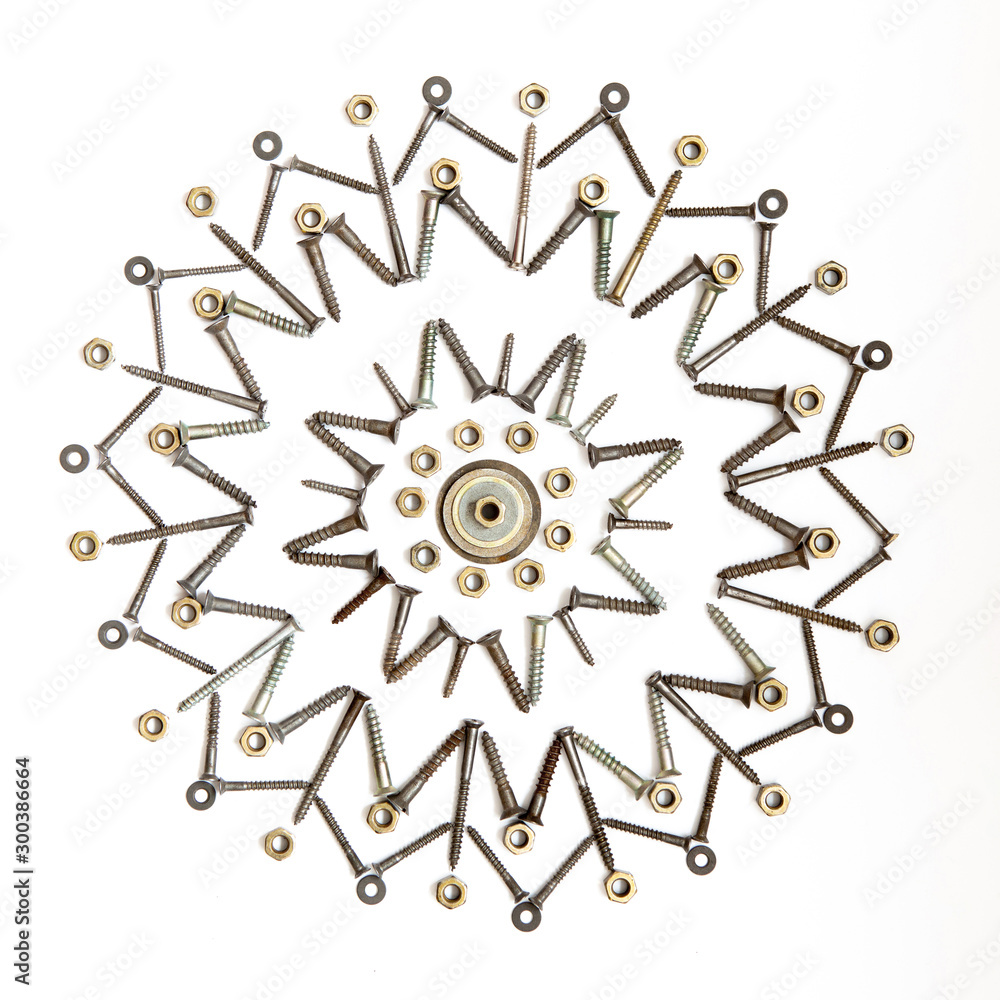 The snowflake of screws, washers, nuts on a white isolated background. View from above. Conceptual photography. The snowflake of screws, washers, nuts on a white isolated background. View from above. Conceptual photography.
