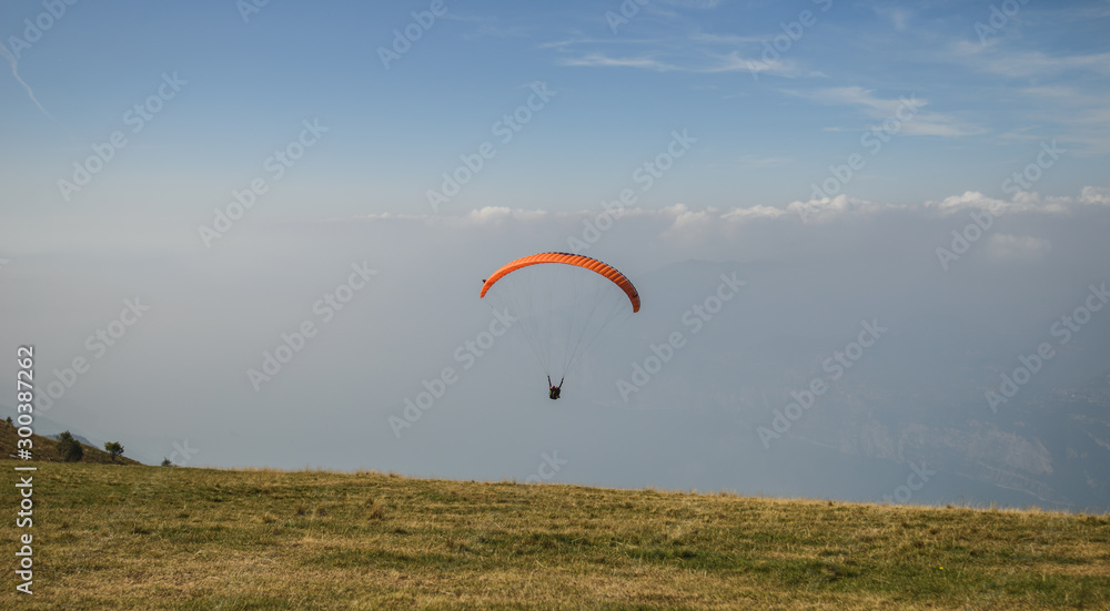 Paraglider flying over the Garda Lake,Panorama of the gorgeous Garda lake surrounded by mountains, Malcesine, Italy Paraglider flying over the Garda Lake,Panorama of the gorgeous Garda lake surrounded by mountains, Malcesine, Italy
