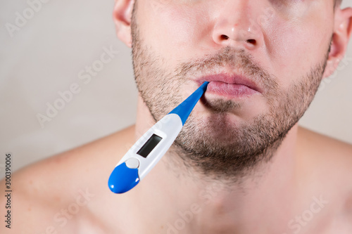 mouth of an unshaven man holding an electronic thermometer in his mouth