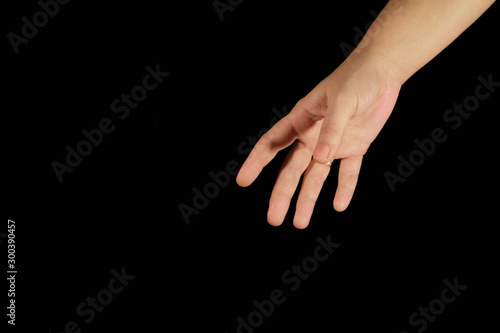 A woman's hand reaches out from a top corner. Isolated women open palms on a black background. Concept of helping hand, relations, help, kindness, choice and support. Hands close-up and copy space.