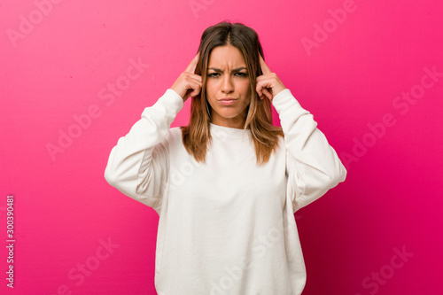 Young authentic charismatic real people woman against a wall focused on a task, keeping forefingers pointing head.