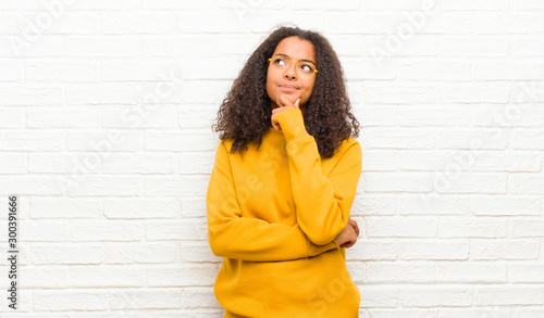 Fotografie young black woman feeling thoughtful, wondering or imagining ideas, daydreaming