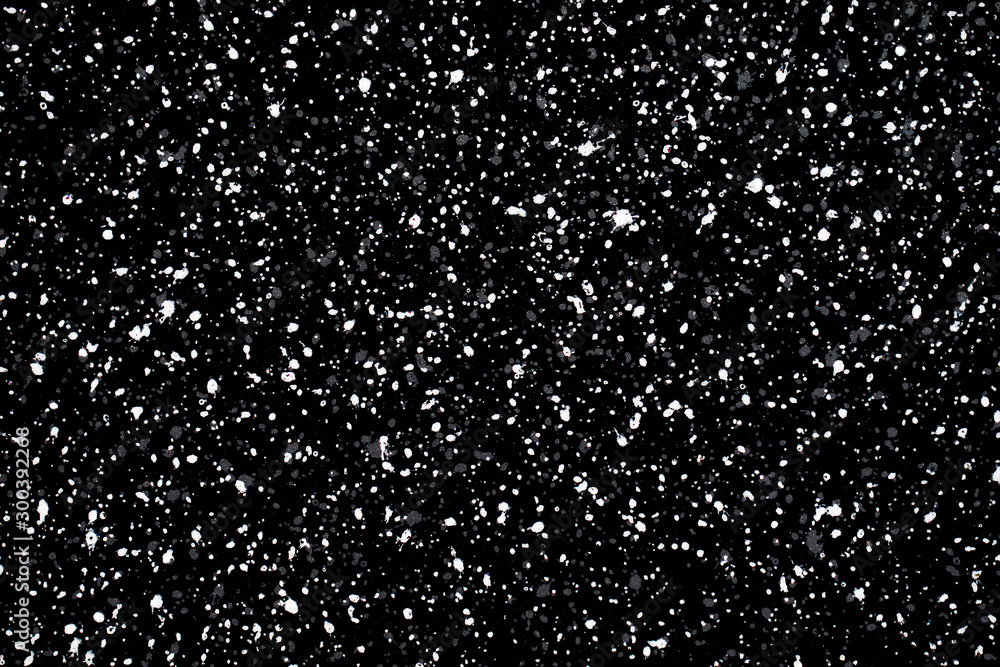 White paint small grainy splashes on black metal surface. Grunge gray and white dots noisy texture for graphic design.