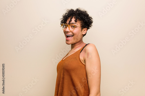 Young african american woman with skin birth mark looks aside smiling, cheerful and pleasant.