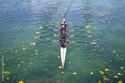 Men's quadruple rowing team on turquoise green lake