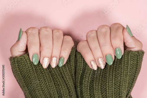 Tela Closeup top view of beautiful two faded colors trendy manicure of  green, pink nails with glossy silver stamping design isolated on pastel pink background