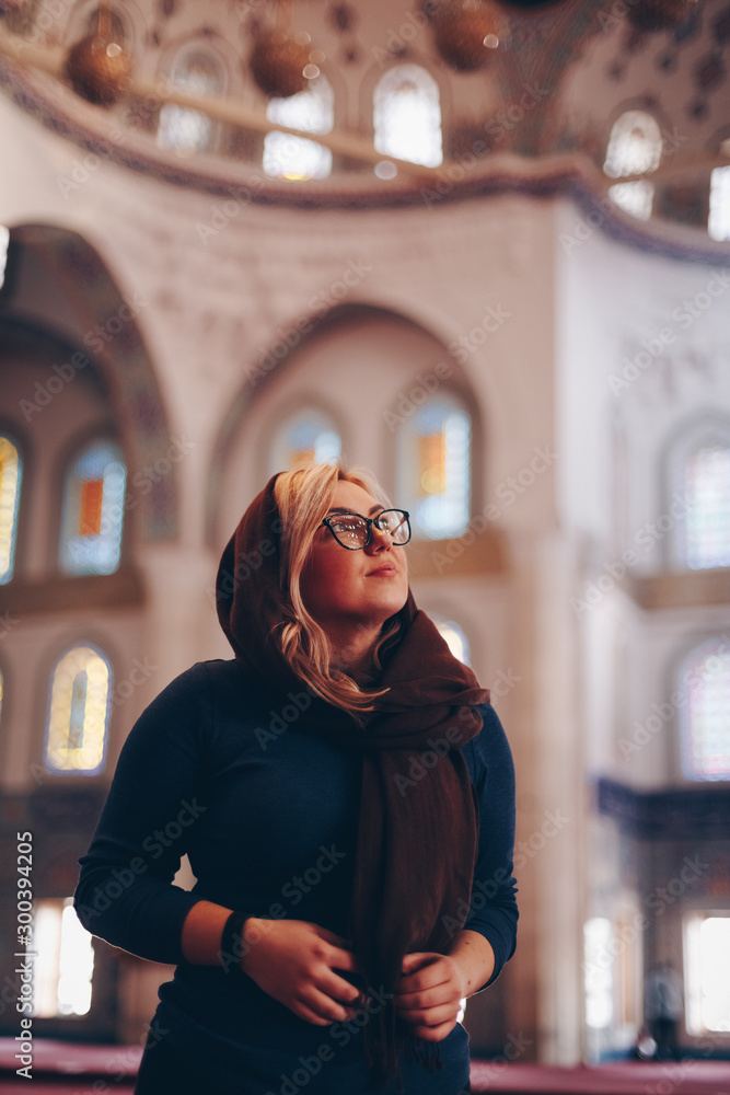 portrait of a beautiful blonde tourist woman visiting kocatepe mosque in ankara, turkey. concept of travelling and experiencing new religions and cultures portrait of a beautiful blonde tourist woman visiting kocatepe mosque in ankara, turkey. concept of travelling and experiencing new religions and cultures