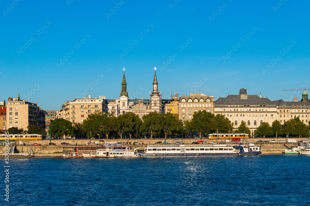 Budapest, Hungary - October 01, 2019: Cityscape of Budapest with Orthodox Cathedral of Our Lady with passenger boats on the Danube river, Budapest, Hungary.