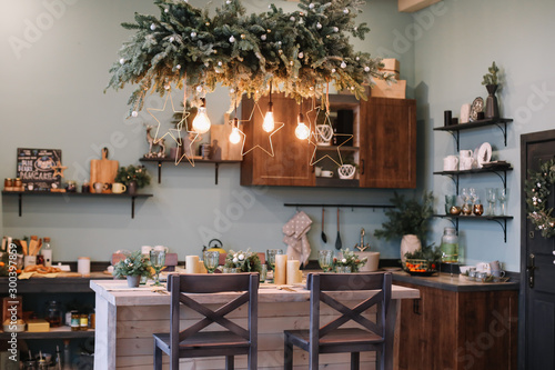 Festive kitchen in Christmas decorations. Christmas dining room. Beautiful New Year decorated classic home interior. New Year and Christmas background