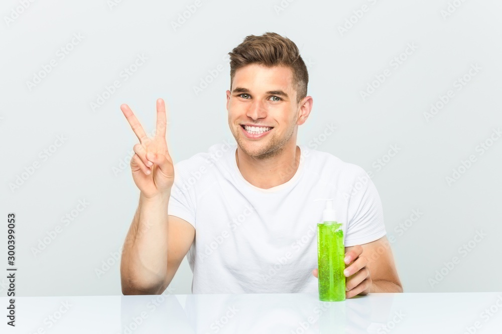 Young handsome man holding a aloe vera bottle showing number two with fingers. Young handsome man holding a aloe vera bottle showing number two with fingers.