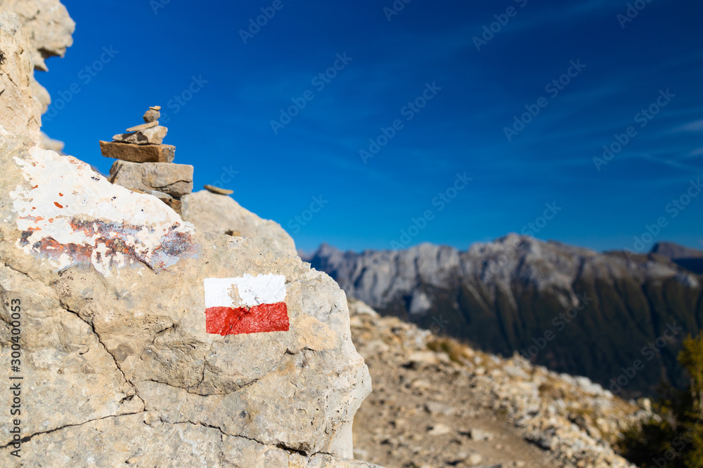 Trekking direction indicators in focus in the foreground. The background of the mountains is blurred. Dolomites Italy