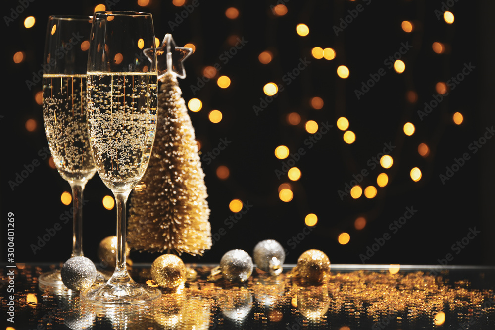 Champagne glasses and baubles against blurred lights background, space for text - obrazy, fototapety, plakaty 
