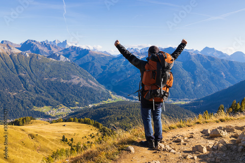 Dolomites. Happy man tourist with a backpack on the background of a beautiful alpine landscape spread his arms. Victory and freedom.