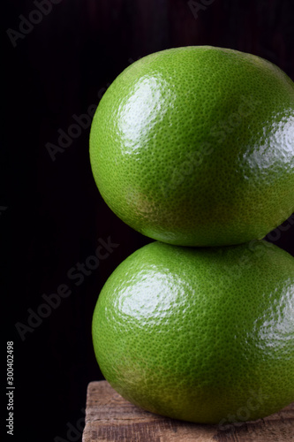 Two whole sweetie fruits against the black background
