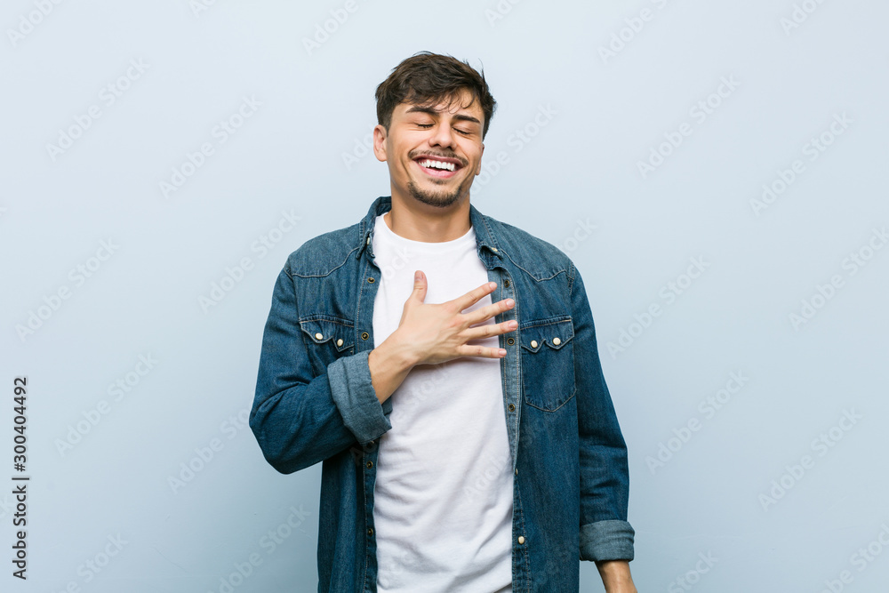 Obraz premium Young hispanic cool man laughs out loudly keeping hand on chest.