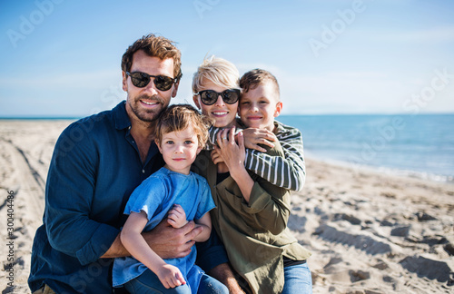 Young family with two small children sitting outdoors on beach.