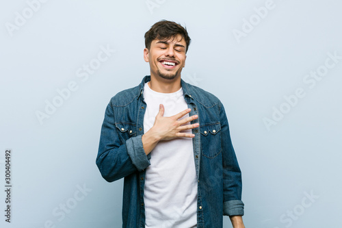 Bild auf Leinwand Young hispanic cool man laughs out loudly keeping hand on chest.