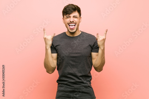 Young hispanic casual man showing rock gesture with fingers