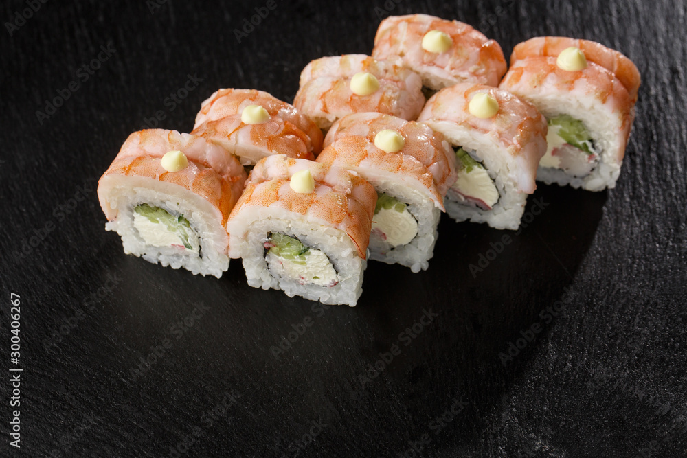 Sushi Rolls with cucumber, shrimp, crab meat and Cream Cheese inside on black slate isolated. Philadelphia roll sushi with shrimp. Sushi menu. Horizontal photo. Sushi Rolls with cucumber, shrimp, crab meat and Cream Cheese inside on black slate isolated. Philadelphia roll sushi with shrimp. Sushi menu. Horizontal photo.