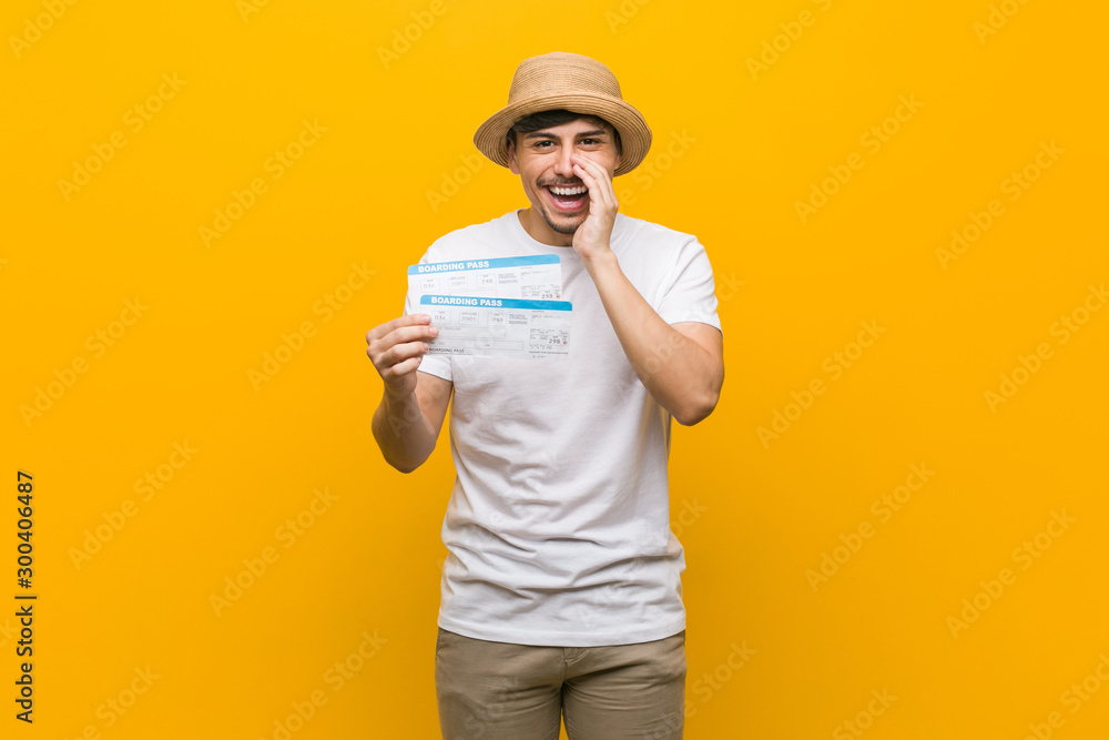 Young hispanic man holding an air tickets shouting excited to front.