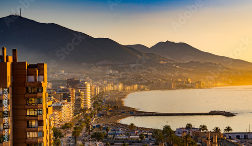 Sunset in Fuengirola, Spain. Golden hour at the coastline with skyscrapers and hills photo