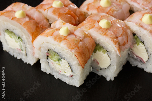 Sushi Rolls with cucumber, shrimp, crab meat and Cream Cheese inside on black slate isolated. Philadelphia roll sushi with shrimp. Sushi menu. Horizontal photo.