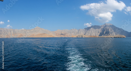 Panorama from the back of a Dhow Boat looking to the Fjords, beautiful blue water, mountains and clouds of Musandam, Oman in the Middle East.