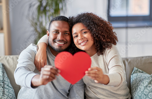 love, valentines day and relationships concept - happy african american couple holding red heart together at home