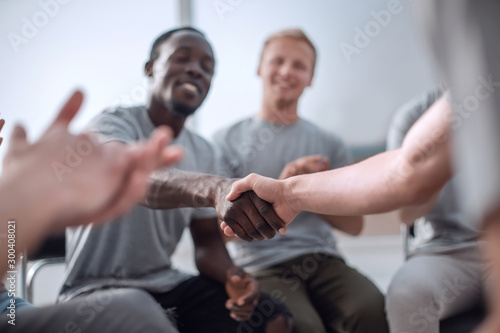 close up. smiling guy shaking hands with his friend