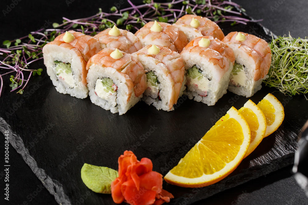Sushi Rolls with cucumber, shrimp, crab meat and Cream Cheese inside on black slate isolated. Philadelphia roll sushi with shrimp. Sushi menu. Horizontal photo. Sushi Rolls with cucumber, shrimp, crab meat and Cream Cheese inside on black slate isolated. Philadelphia roll sushi with shrimp. Sushi menu. Horizontal photo.