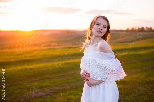 Beautiful smiling woman in a field at sunset